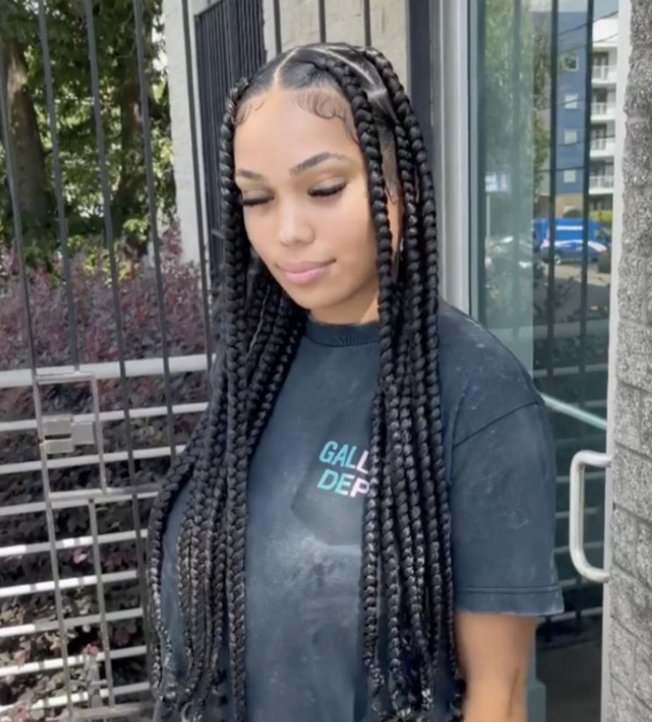 Client wearing long jumbo knotless braids with curly ends and laid edges outside the Ani Braids studio in Lanham, Maryland