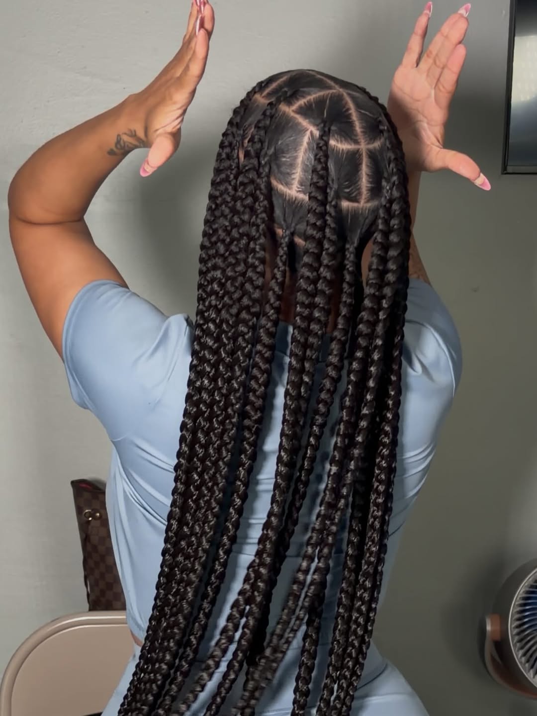 Client holding up long jumbo knotless braids to show the clean parting and smooth, even braid pattern, by Ani Braids in Lanham, Maryland