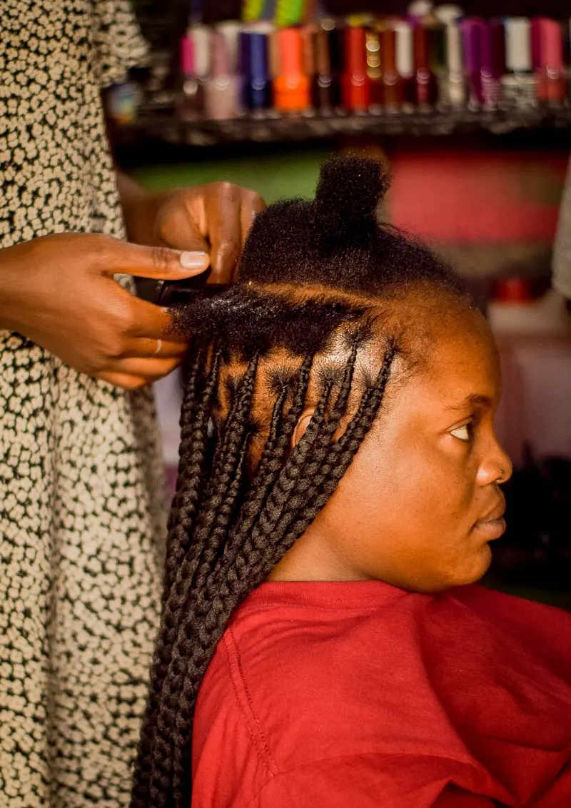 African hair braiding in a colorful salon setting