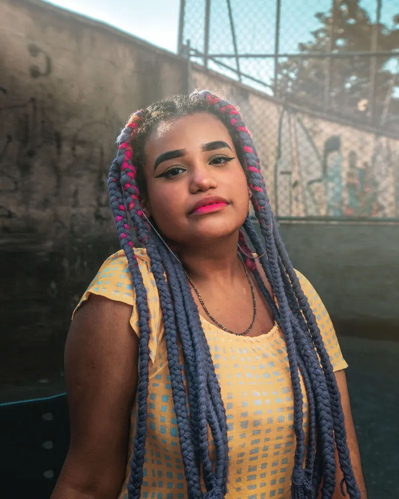 Woman with vibrant braided hair standing outdoors in summer heat