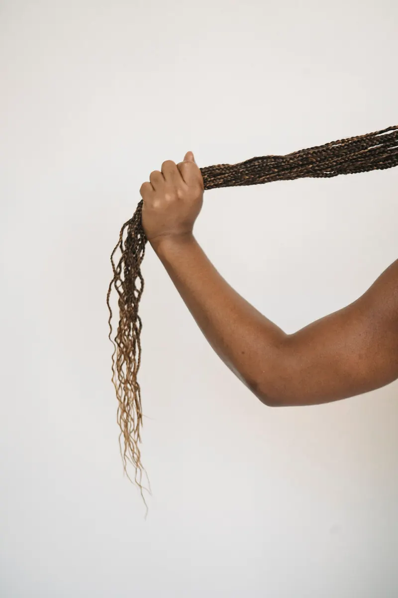A woman gently holding one of her long braids, showing the smooth, well maintained texture that comes from consistent aftercare