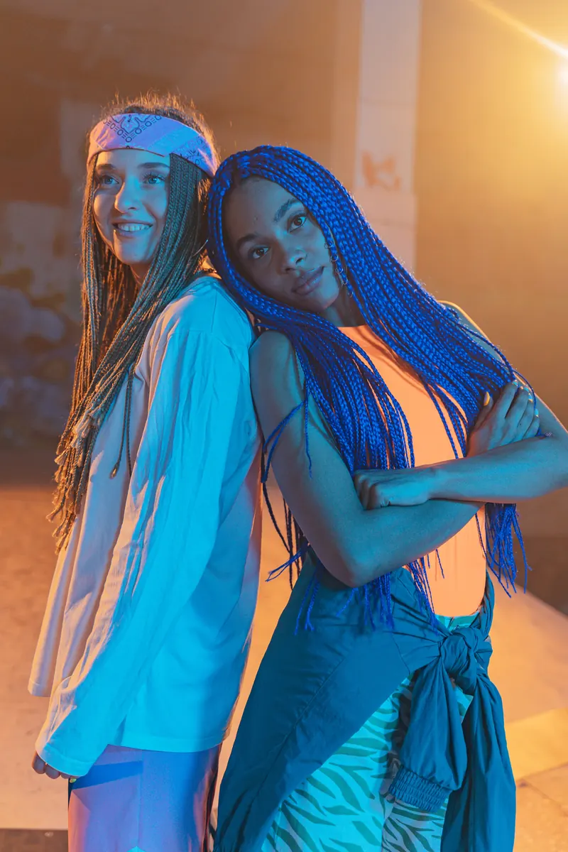 Two women with colorful box braids posing together indoors